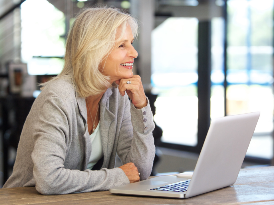 Ältere Frau mit graublonden Haaren an einem Laptop visualisiert Aktivrentengesetz