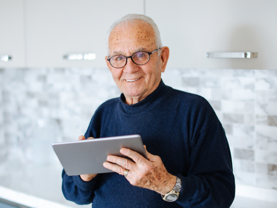 Älterer Mann mit Tablet in der Hand symbolisierend für Aktivrente